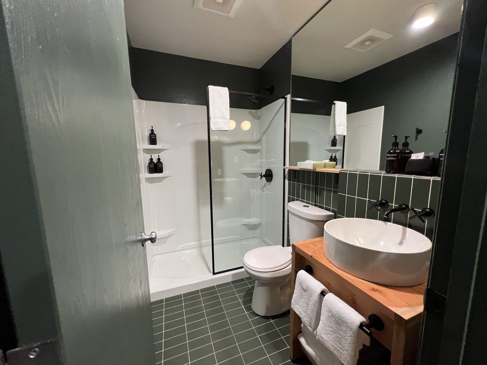 Guest bathroom at a Glacier National Park lodge near Whitefish, featuring a vessel sink, dark fixtures, and a glass shower.