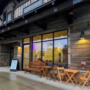 Coffee shop exterior in Glacier National Park with a rustic wooden facade and outdoor seating along the storefront.