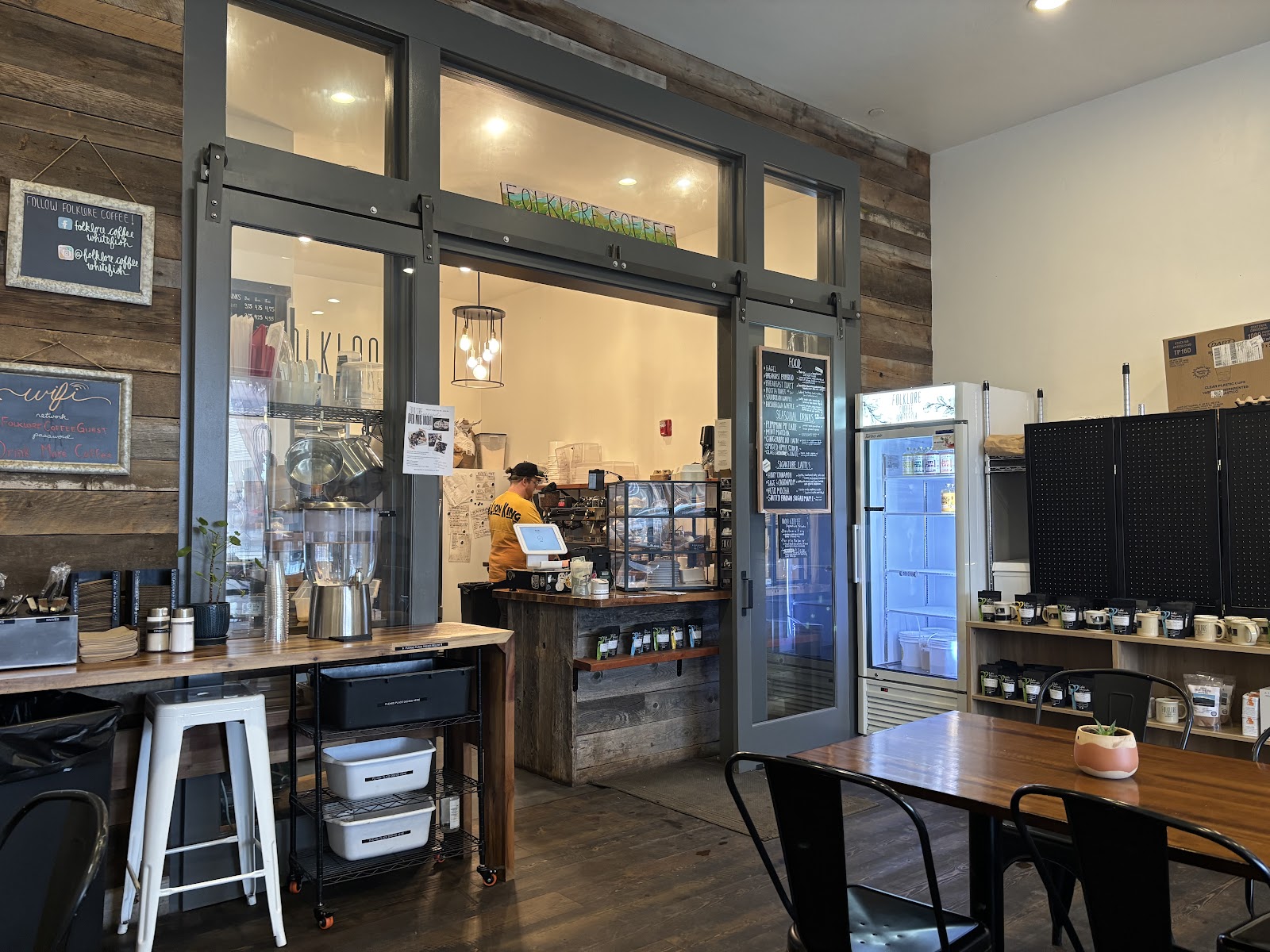 Interior of a Glacier National Park cafe with rustic wood walls, a coffee bar, and refrigerated display case.