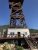 Glacier Ziplines tower rises above a wooden deck at Glacier National Park, with a clear blue sky overhead.
