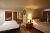 Cozy hotel room in a Yellowstone National Park lodge, featuring a large bed, nightstand lamps, and warm lighting.