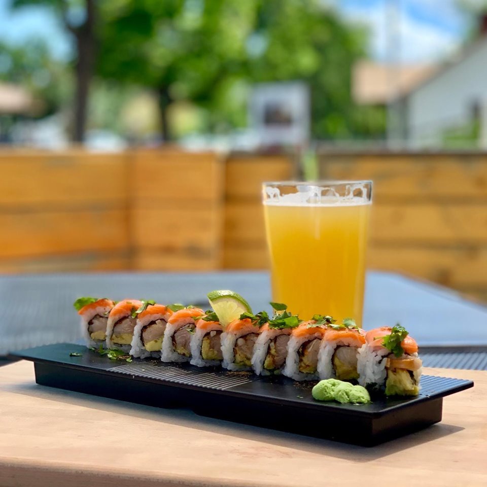 Sushi platter with wasabi and lime on a black tray, set on an outdoor table in Glacier National Park.