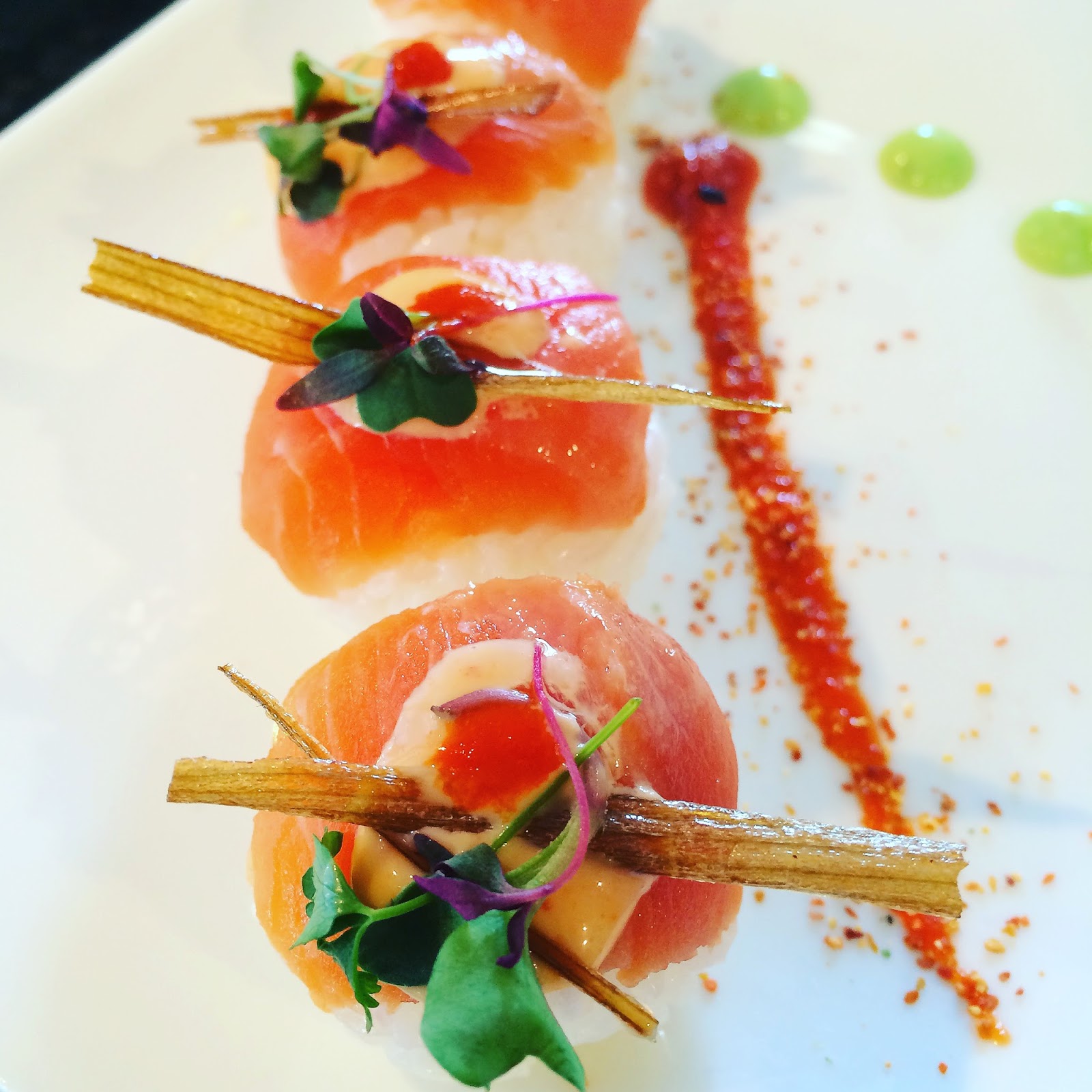 Salmon nigiri sushi plate with greens and crispy garnish presented on a white plate at Glacier National Park.