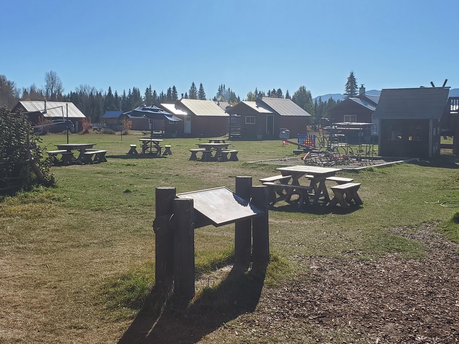 Polebridge Mercantile area in Glacier National Park features wooden picnic tables and rustic storefronts on a sunny day.