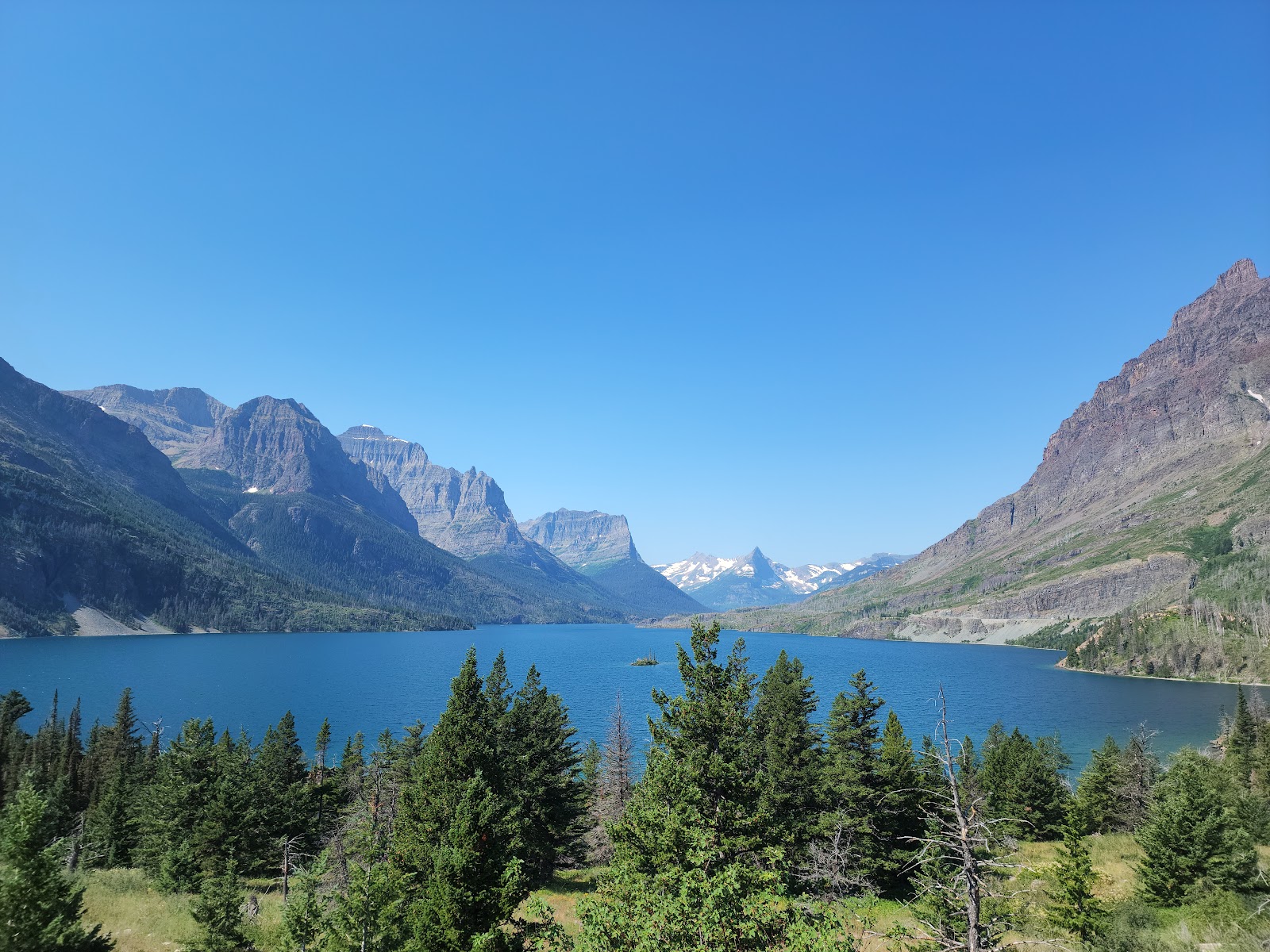 Glacier National Park: rugged mountains rise over a bright blue lake framed by evergreen forests near the Swift Creek area.