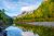Autumnal lakeside scene in Glacier National Park with calm waters reflecting pine forests and distant peaks.