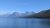 Glacier National Park lake and mountain range under a vivid blue summer sky, with a forested shoreline.