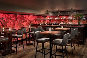 Bar seating and a red-lit wall backdrop inside Latitude 48 Bistro at Glacier National Park.