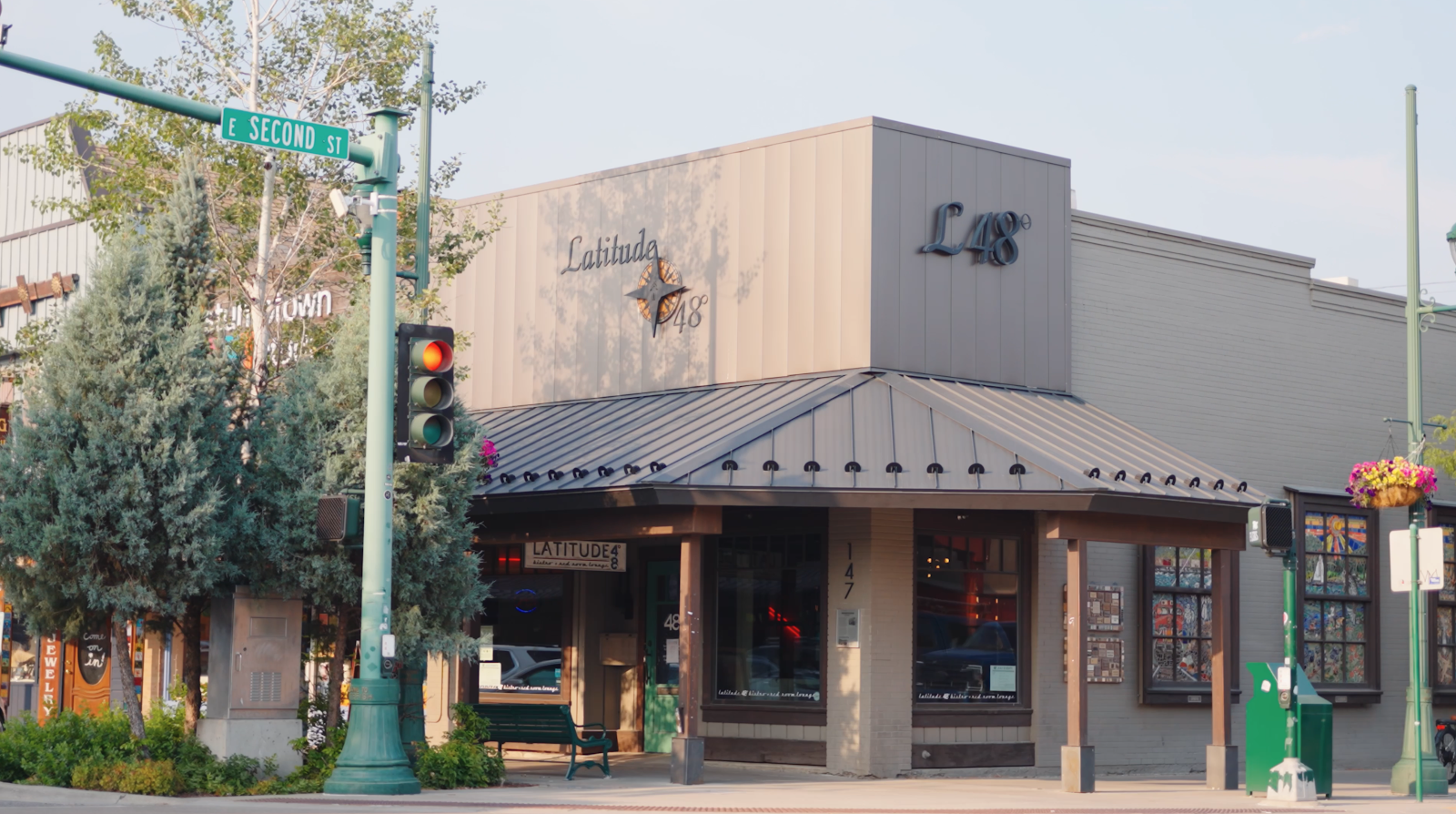 Storefront of a bistro in Glacier National Park's gateway town, with a green street sign and outdoor seating.