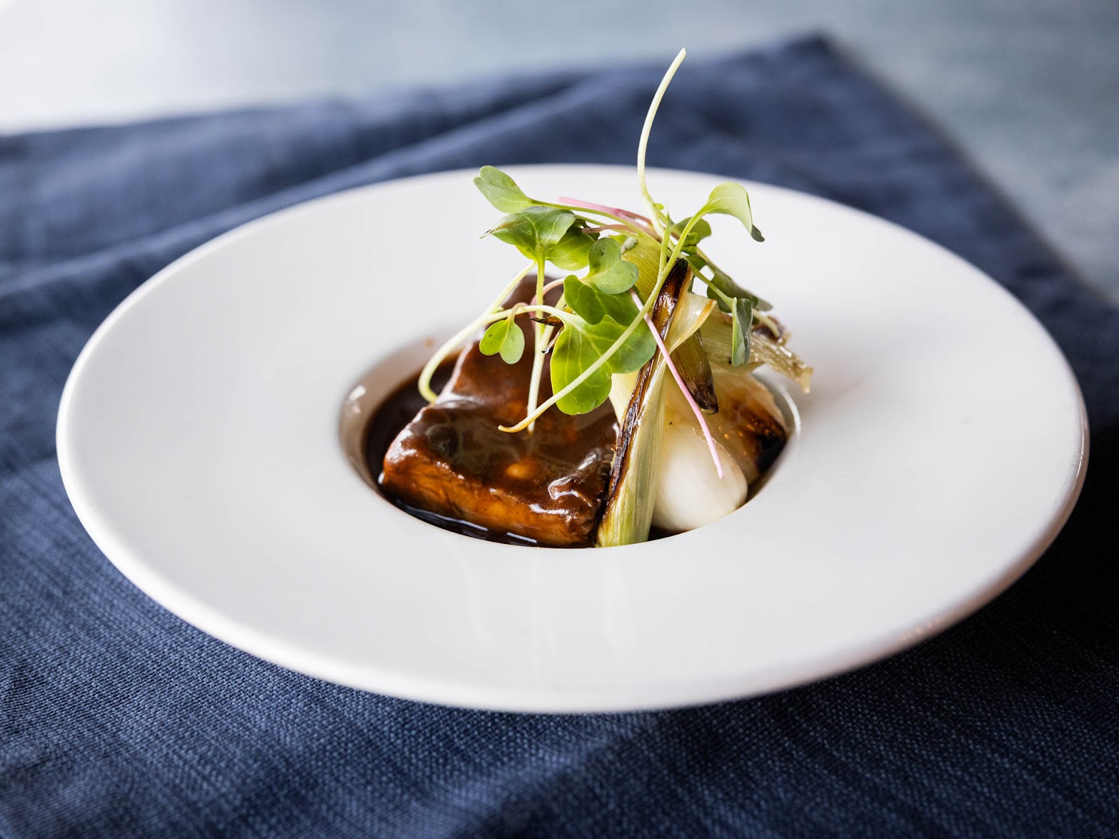 Gourmet plated dish served in Glacier National Park, showcasing modern cuisine with microgreens and a rich sauce.