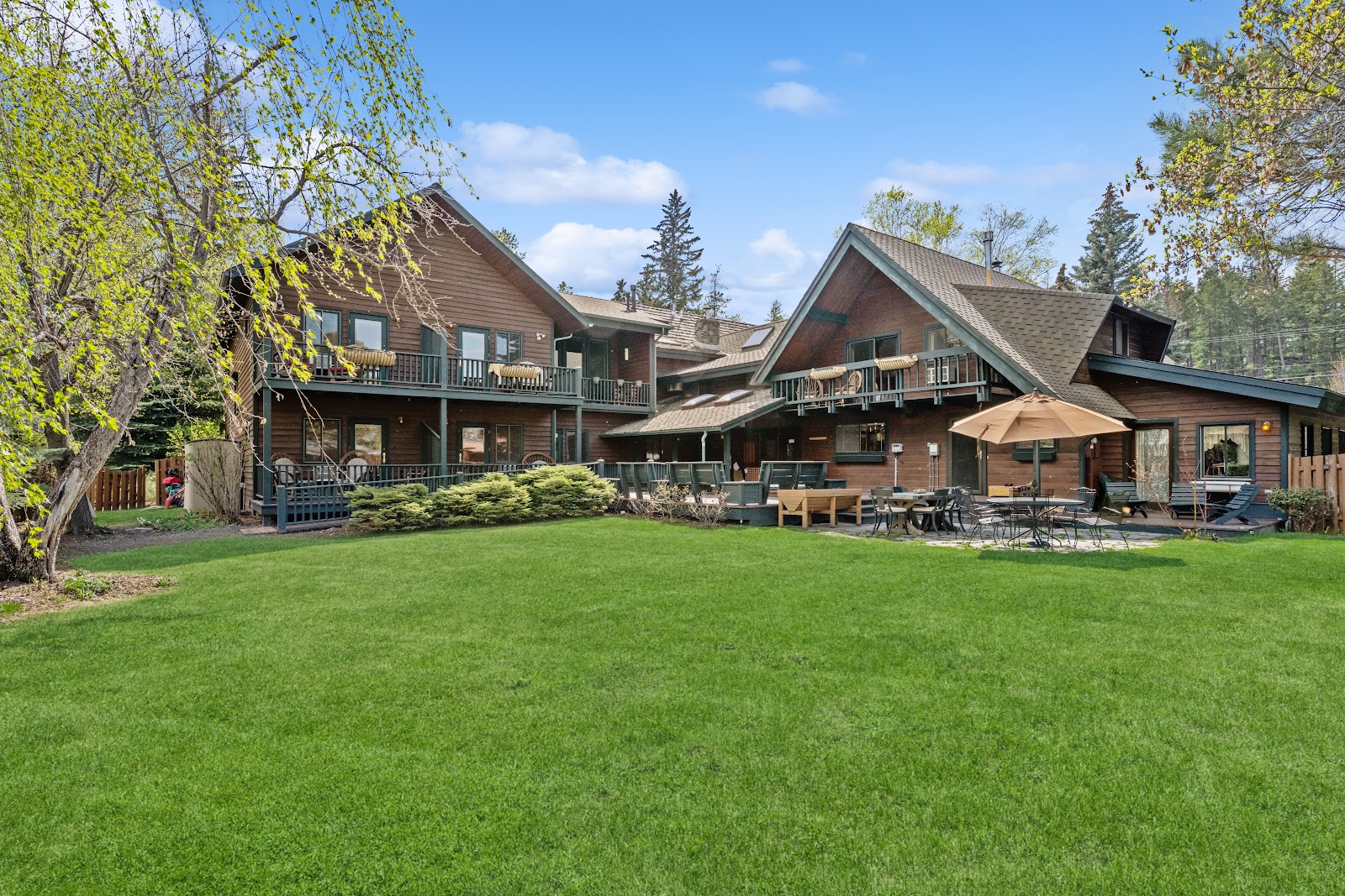Lodge complex at Glacier National Park featuring wood exteriors and a lush green lawn.