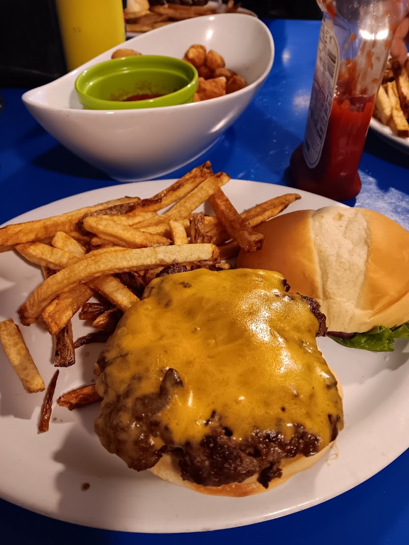 Cheeseburger with melted cheese and a heap of fries on a white plate with a ketchup bottle, Yellowstone National Park.