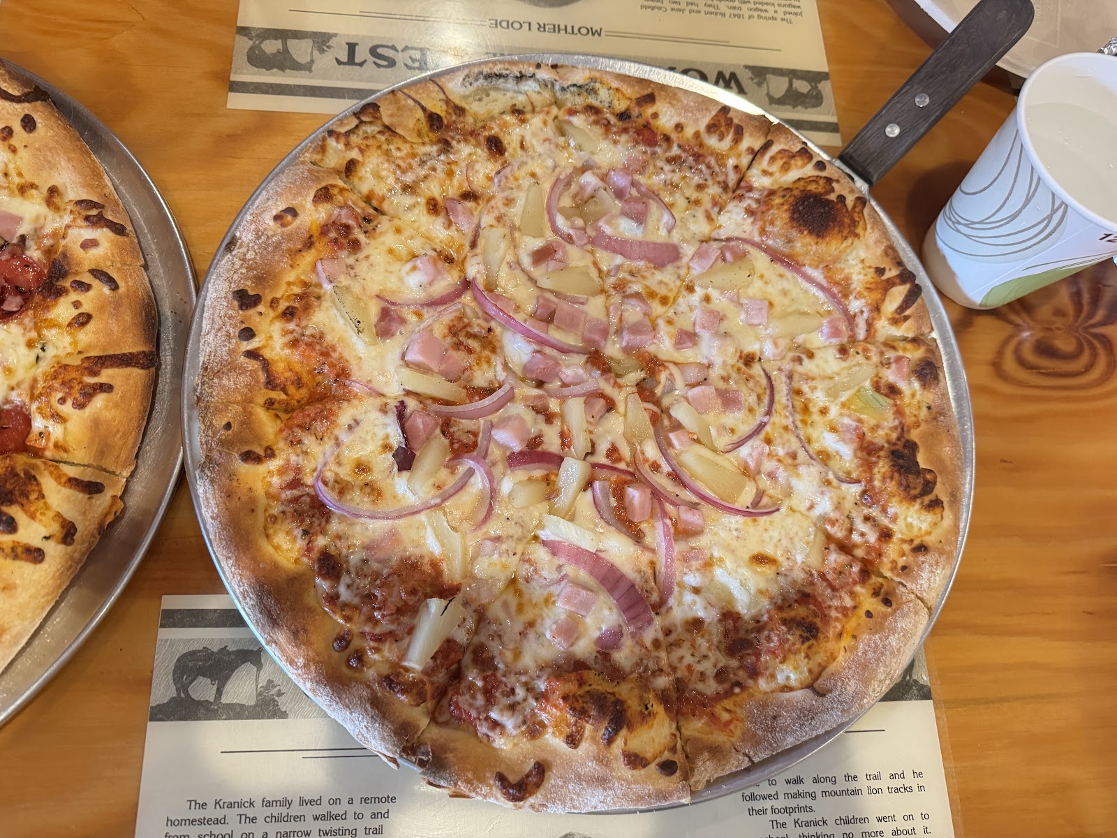 Pizza dinner at a bustling dining table in West Glacier, Glacier National Park, inside a casual pizzeria near the park entrance.