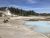 Norris Back Basin geothermal area at Yellowstone National Park with steam vents and a milky blue pool.
