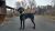 Dog with curly black fur on a paved driveway at a lodge in Glacier National Park, surrounded by leafless trees.