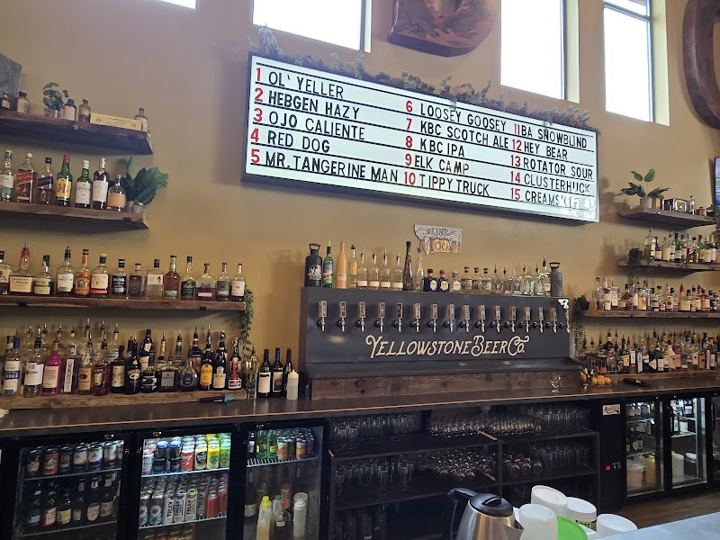 Bar interior at Yellowstone National Park with bottled spirits on shelves, beer taps, and a large menu board.