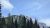 Avalanche Creek Picnic Area in Glacier National Park, with snow-capped peaks rising beyond a pine forest.