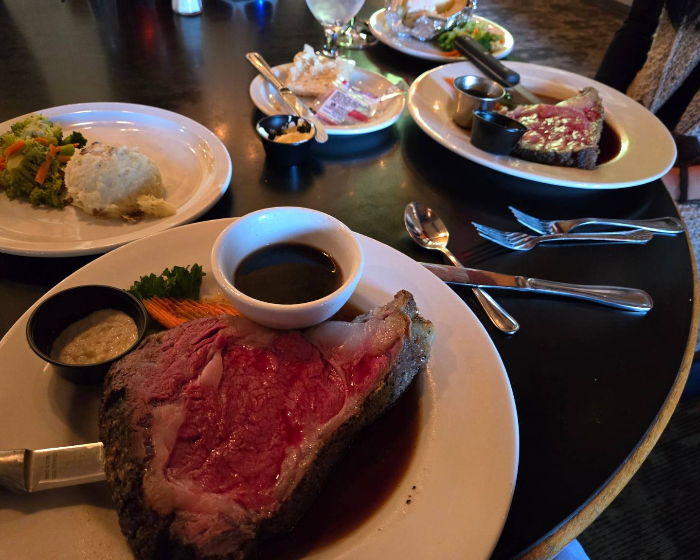 Ribeye steak dinner at a Glacier National Park restaurant with a small cup of sauce, mashed potatoes, and vegetables.