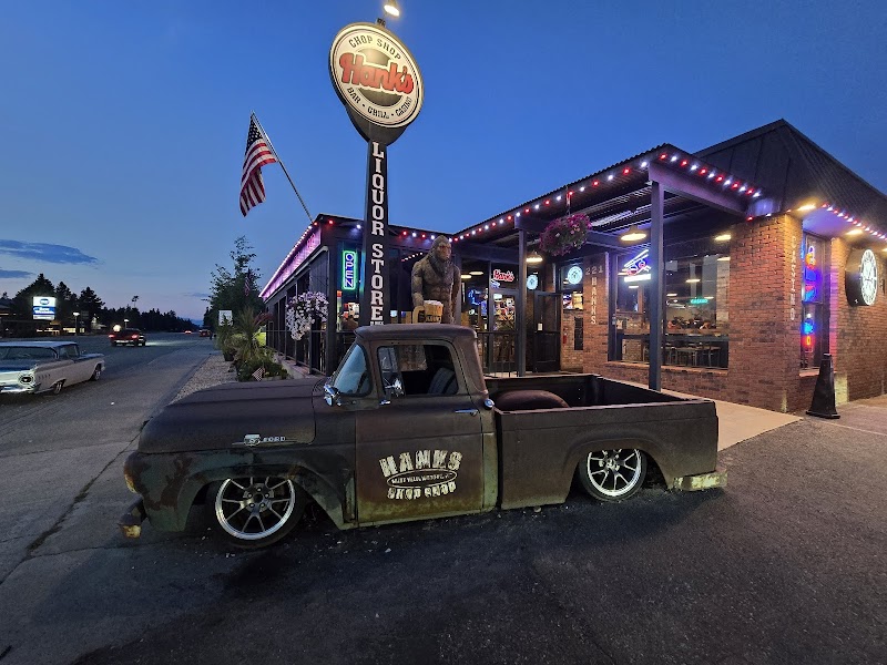 Twilight in Yellowstone National Park: rusted vintage pickup sits in front of a lit brick restaurant with flag and neon signs.