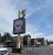 Tall sign featuring a bear statue atop a rustic eatery sign in Glacier National Park, with a clear blue sky.