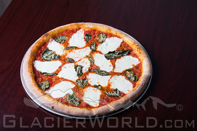 Pizza with fresh mozzarella and basil on a round crust at Glacier National Park restaurant setting.