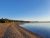 Yellowstone National Park shoreline with a sandy beach, calm blue lake, and pine forest under a clear sky.