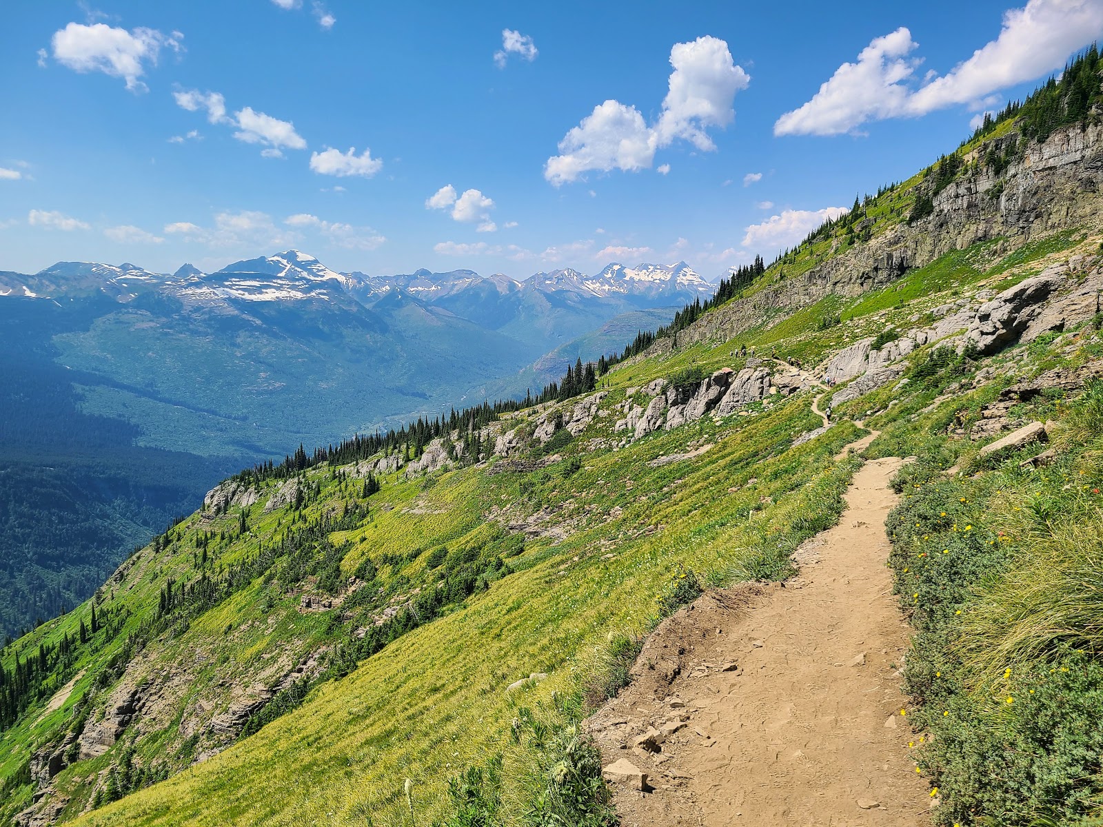 Highline Trail Trailhead winds along a rugged alpine slope with snow-capped peaks in Glacier National Park.