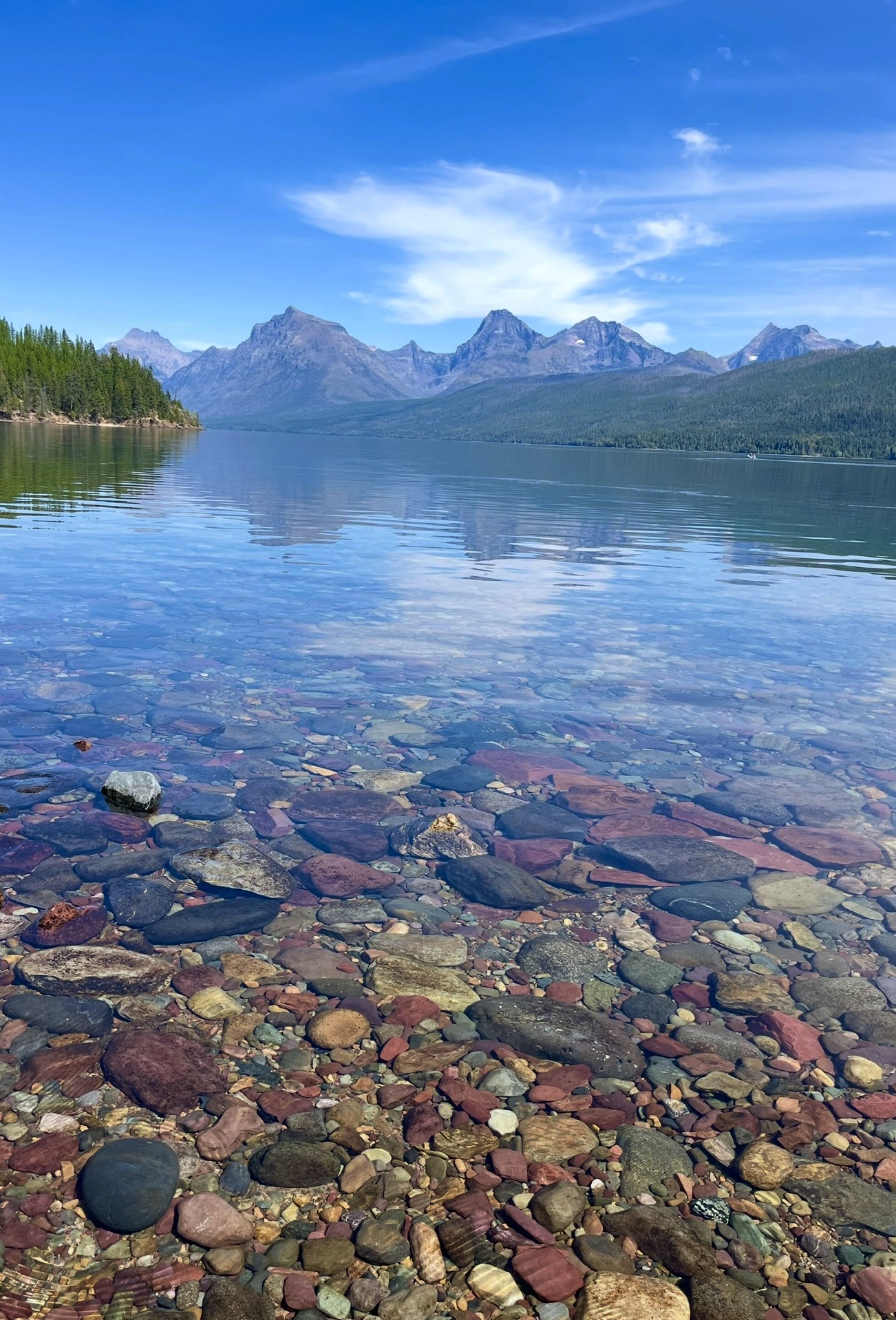 Lake McDonald shoreline at Glacier National Park with crystal water and multicolored, smooth stones along  — Apgar Campground