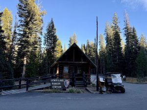 Entrance to a lakeside campground with a wooden sign and forested backdrop