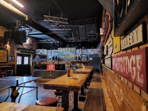 Interior of a rustic Glacier National Park bar and grill, with wooden benches, long tables, and vintage signage.