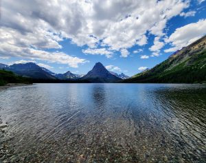 Two Medicine Picnic Area beside a clear alpine lake with rugged peaks in Glacier National Park.