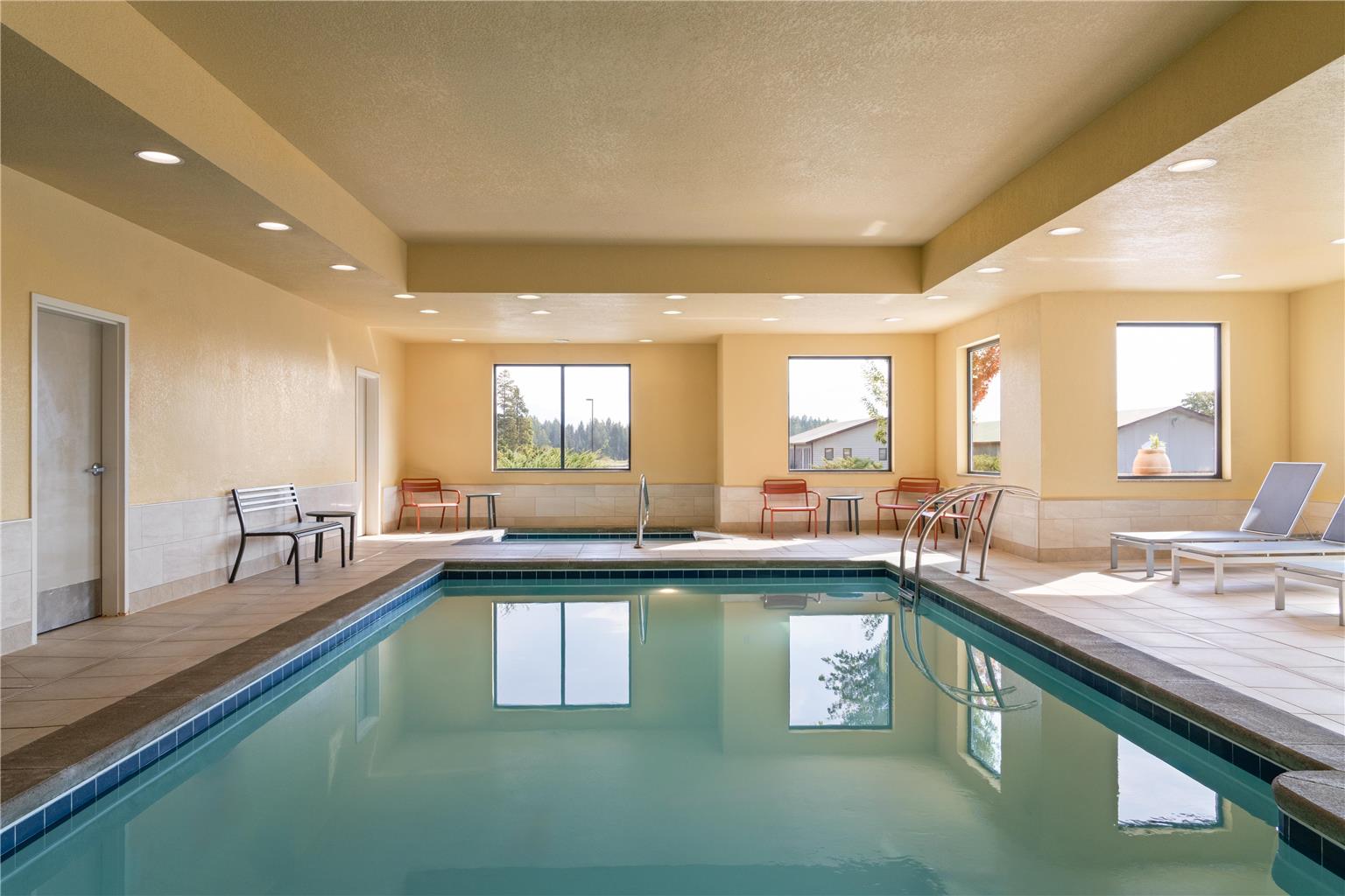 Indoor pool inside a lodge in Whitefish near Glacier National Park, with large windows and seating along the walls.
