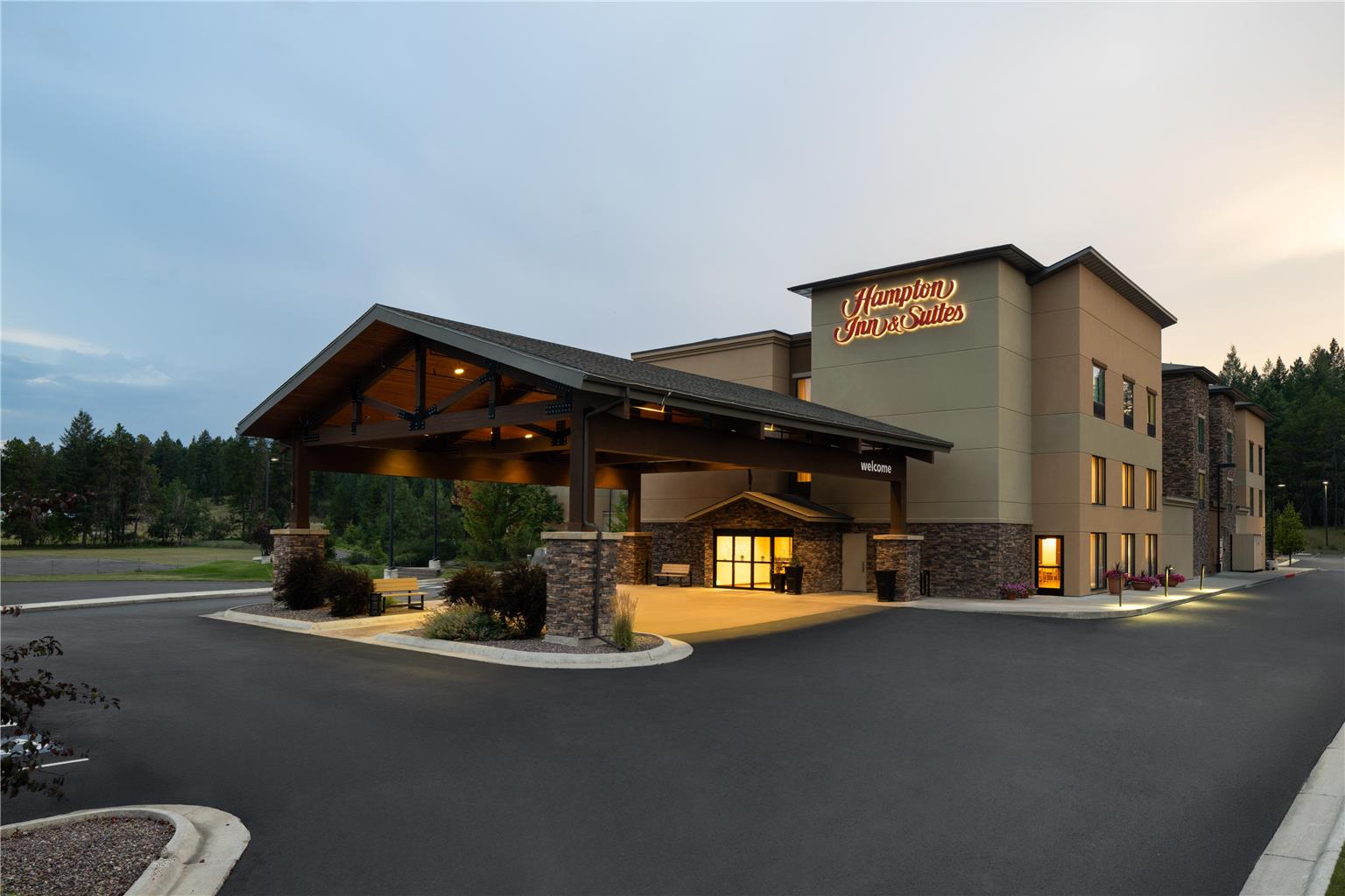 Whitefish area hotel exterior near Glacier National Park at dusk, with porte-cochere and warm lighting.