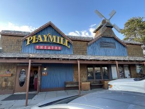 Exterior view of a rustic theatre storefront with a wooden facade and marquee