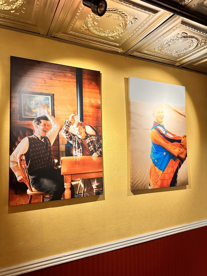Yellowstone National Park interior features two large portraits on a gold wall: laughing men at a table and a person in a superhero cape.