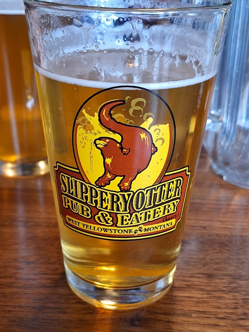 Pint glass with a yellow logo showing a red mammoth and bold text, West Yellowstone, Montana, in Yellowstone National Park.