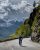 Biker pedals along Going-to-the-Sun Road, Glacier National Park, with snow-dusted peaks and dramatic cliffside scenery.