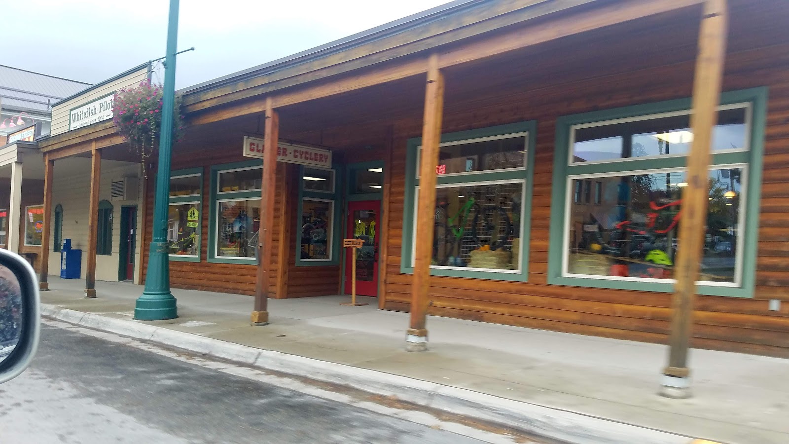 Glacier National Park gift shop storefront housed in a wooden building with teal-trimmed windows and bicycle gear on display.