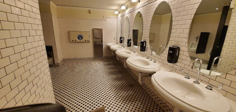 Row of white ceramic sinks with mirrors along tiled walls in a public restroom at Yellowstone National Park.
