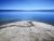 Yellowstone Lake Overlook Trail showcases a rocky shoreline with calm blue Yellowstone Lake and distant mountains under a clear sky.