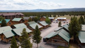 Rustic cabin exterior with wraparound porch and evergreen trees