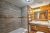 Rustic Yellowstone National Park cabin bathroom with gray tiled shower, wood-paneled walls, and a granite countertop vanity.