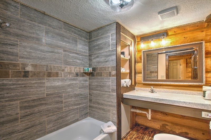 Cozy cabin bathroom with gray tiled shower wall, wooden accents, and a granite vanity in Yellowstone National Park.