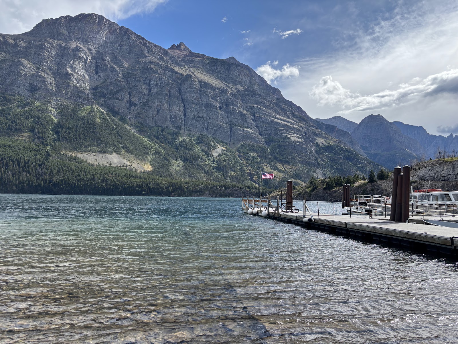 Saint Mary Lake at Glacier National Park, a tranquil lakefront with a wooden dock against rugged peaks.