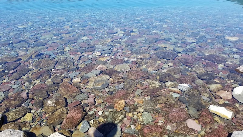 Apgar Beach along Lake McDonald in Glacier National Park features clear water and a colorful pebble beach.