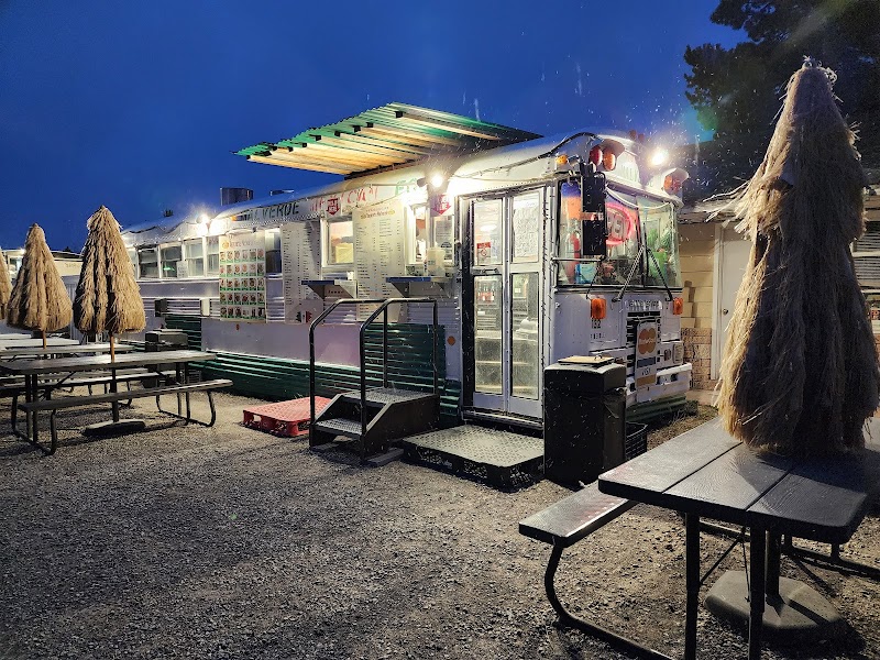 Night scene at a bright food truck in Yellowstone National Park, with menu boards and outdoor picnic tables.