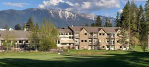 Lodging complex near Glacier National Park sits on manicured greens with snow-capped peaks in the background.