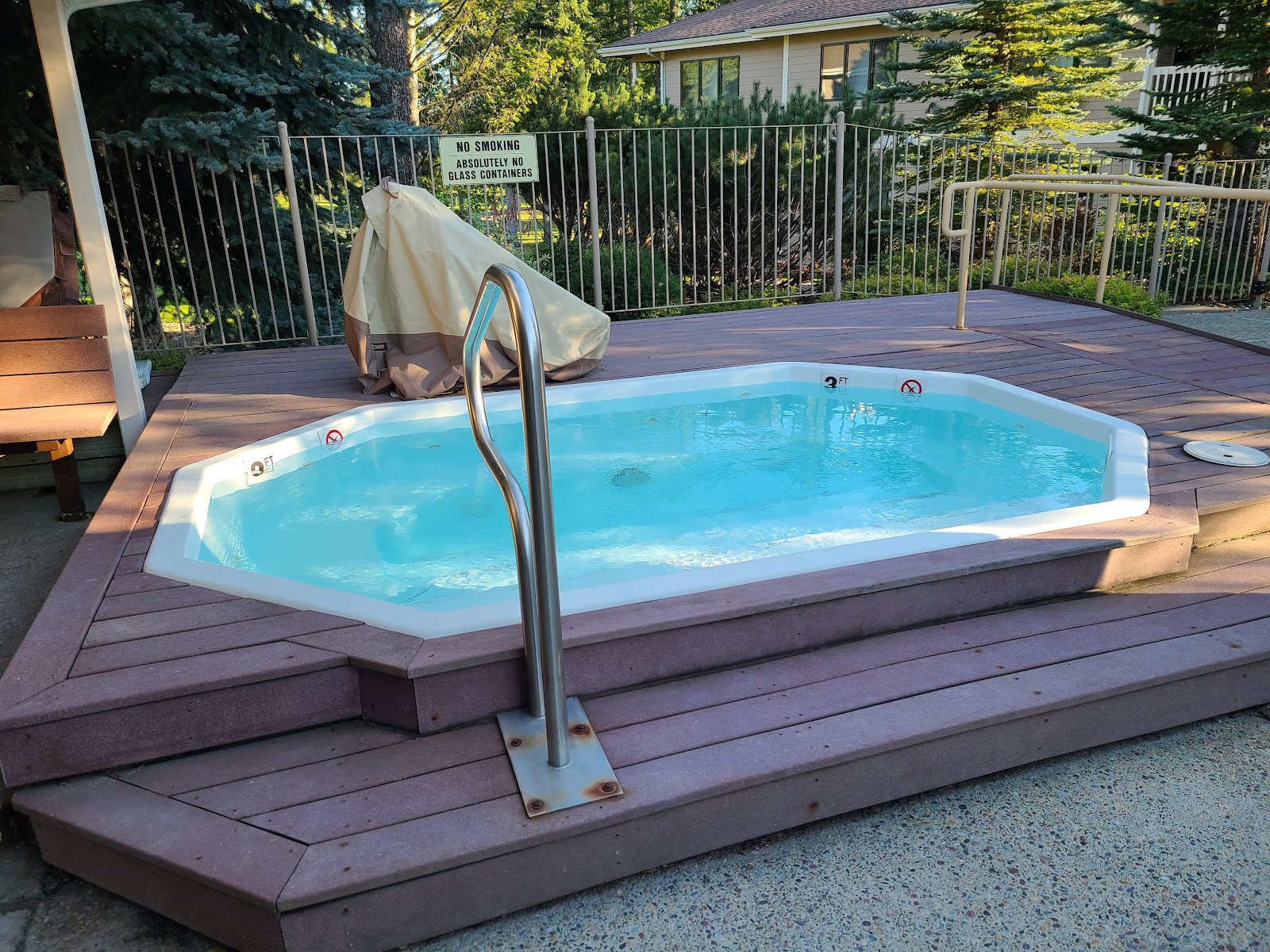 Outdoor hot tub on a wooden deck behind a fence at a resort near Glacier National Park.