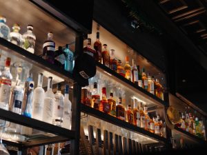 Liquor bottles line glass shelves inside a Glacier National Park restaurant bar, warmly lit and inviting.