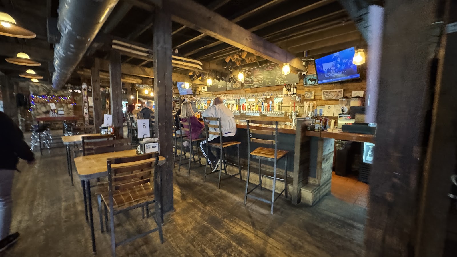 Interior of a rustic bar at Glacier National Park with wooden beams, warm lighting, and a long counter.